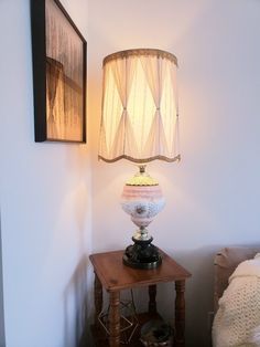 a lamp sitting on top of a wooden table next to a wall with pictures above it