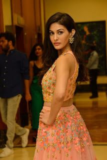 a woman in a pink dress posing for the camera while others look on from behind her