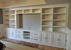 an empty room with white cabinets and drawers