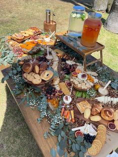 a picnic table with food and drinks on it in the middle of a grassy area