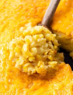 a spoon with some food in it on top of a pan filled with corn casserole