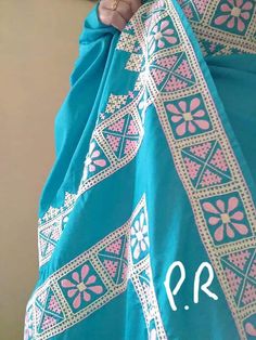 a close up of a person wearing a blue and pink shawl with the word p r written on it