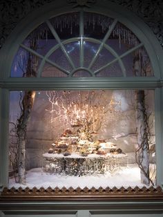 a display window with an elaborate table and chandelier in the center surrounded by snow