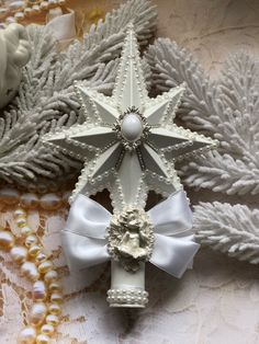 an ornament made to look like a snowflake with pearls and bows