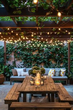 an outdoor dining area with lights strung from the ceiling and wooden table surrounded by potted plants