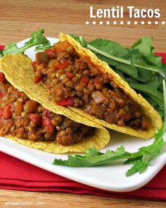 two tacos on a plate with lettuce and tomatoes