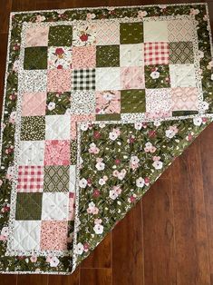 a quilted table runner on the floor with flowers and checkered squares in it