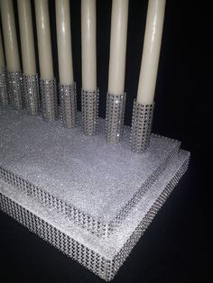 several candles are lined up on a silver table cloth with sequins and beads