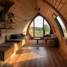 a living room filled with furniture next to a large window on the side of a wooden wall