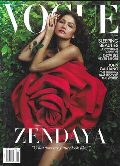 a woman in a red dress laying on the cover of a magazine with greenery around her