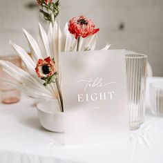 there is a card that says table eight on it next to some vases with flowers