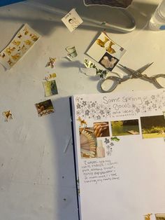 an open book sitting on top of a table next to scissors and other items that include photos