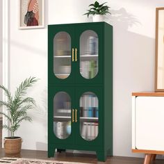 a green bookcase with glass doors in a living room next to a potted plant