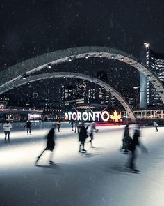 people skating on an ice rink at night in toronto, canada with the city lights lit up behind them