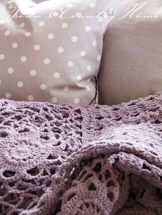 a bed with a blanket and pillows on top of it next to a pillow that has polka dots