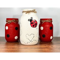 three painted mason jars with ladybugs on them