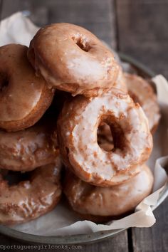 a pile of glazed doughnuts sitting on top of a white paper towel in a bowl