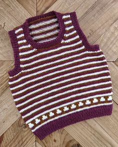 a purple and white sweater sitting on top of a wooden floor