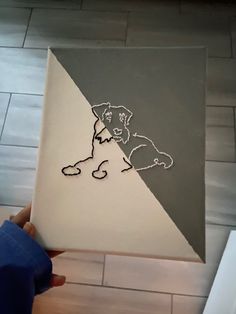 a person holding up a piece of art with a dog on it's side