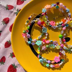 a yellow plate topped with lots of bracelets and beads on top of a table