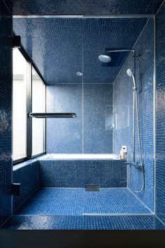 a blue tiled bathroom with a shower and toilet in the corner, it looks like something out of space