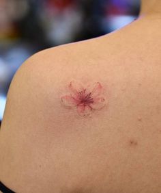 the back of a woman's shoulder with a flower tattoo on her left side