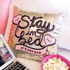 a laptop computer sitting on top of a desk next to a pillow and bowl of popcorn