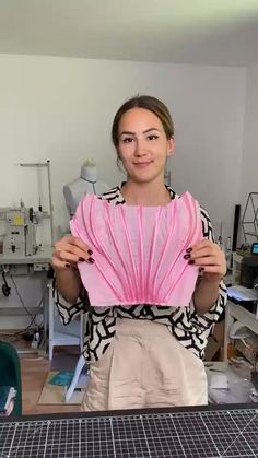 a woman holding up a pink object in her hands