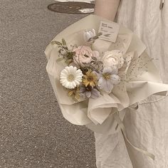 a woman holding a bouquet of flowers on the street