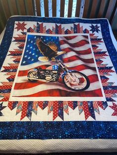 an american flag quilt with a motorcycle and eagle on the front is displayed in a crib