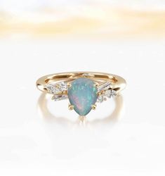 an opal and diamond ring on a white surface with the top half in yellow gold