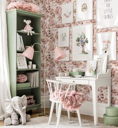 a white desk sitting in front of a green book shelf filled with books and stuffed animals