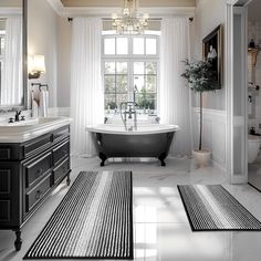 a bathroom with a claw foot tub, chandelier and rugs on the floor