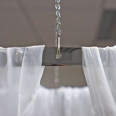 the curtain is hanging down from the ceiling in front of the window with white drapes