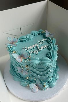 a blue birthday cake in a white box with butterflies on the top and happy birthday written on it