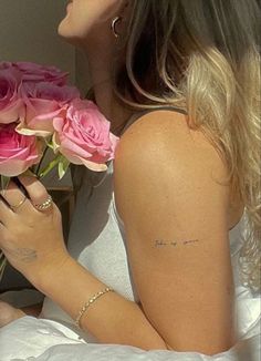 a woman laying in bed with pink roses and writing on her arm that says, i love you