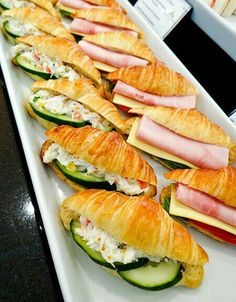 many sandwiches are lined up on a long white platter