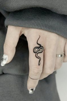 a woman's hand with a tattoo on it and a snake design on the middle finger