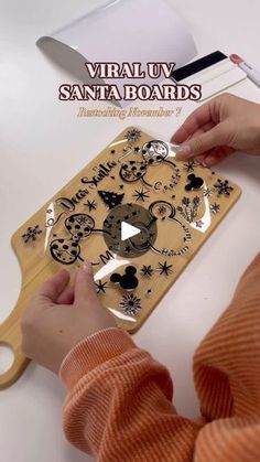 a person using a wooden cutting board with mickey mouse faces on it and the words virtual santa boards