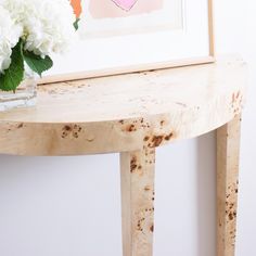 a vase with white flowers sitting on top of a table next to a framed painting