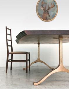 a wooden table and chair in front of a painting