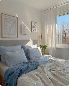 a bed with blue and white sheets in a bedroom next to a large window overlooking the trees