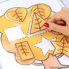 a person cutting out some paper shapes on a piece of paper that is sitting on top of a table