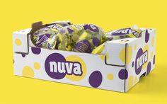 a box filled with lots of purple and yellow candy on top of a yellow background