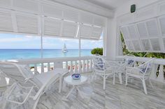 a balcony with white furniture overlooking the ocean