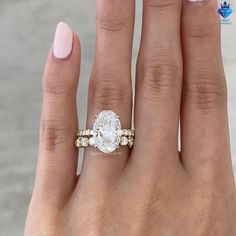 a woman's hand with a pink manicured nail polish and an oval shaped diamond ring