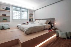 a bed sitting on top of a wooden platform in a bedroom next to a window