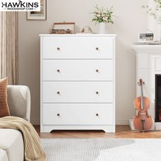 a white chest of drawers sitting next to a fire place with a violin on it