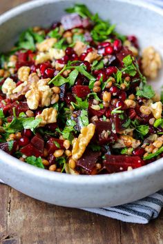 a salad with beets, walnuts and parsley in a white bowl on a wooden table