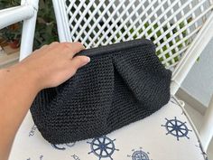 a hand holding a black purse on top of a white chair